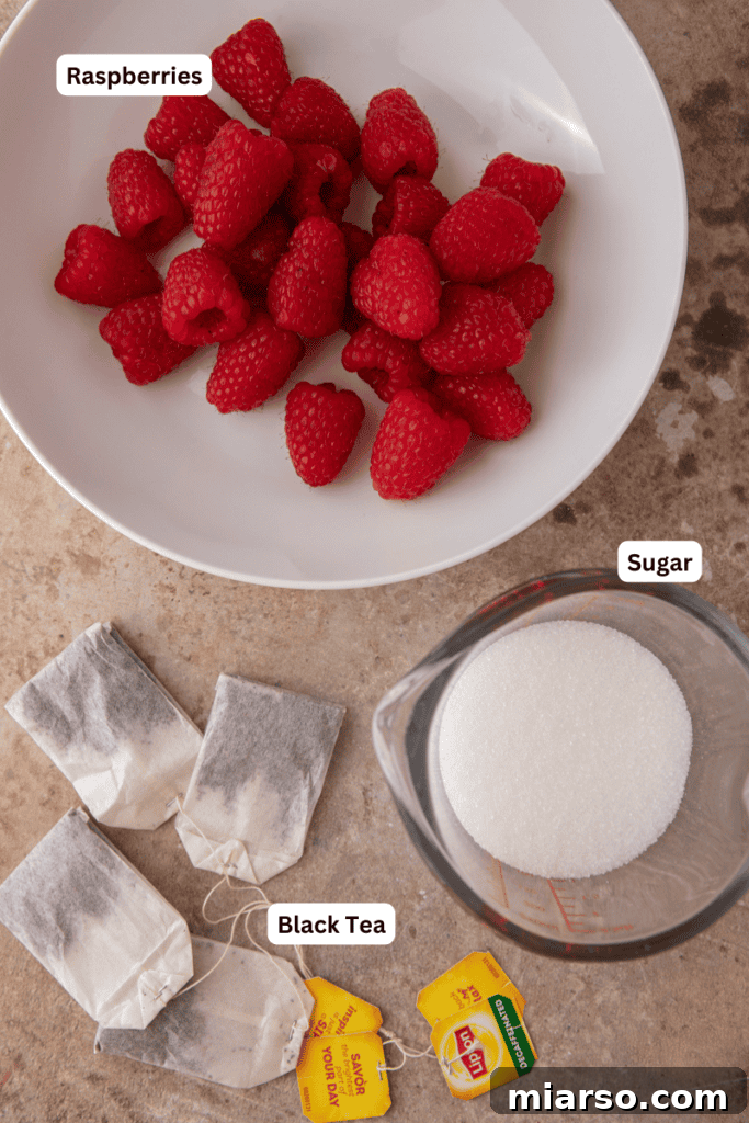 Close-up of fresh ingredients for Raspberry Iced Tea recipe, including raspberries, tea bags, and sugar