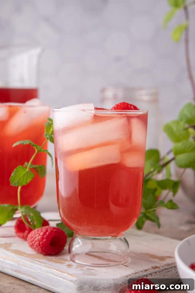 Raspberry Iced Tea recipe in a glass with ice and fresh raspberries as garnish