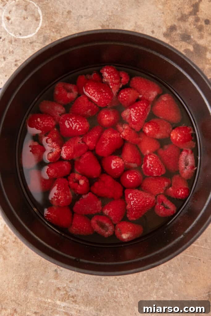 fresh raspberries, water, and sugar in a pot, ready to be cooked into syrup