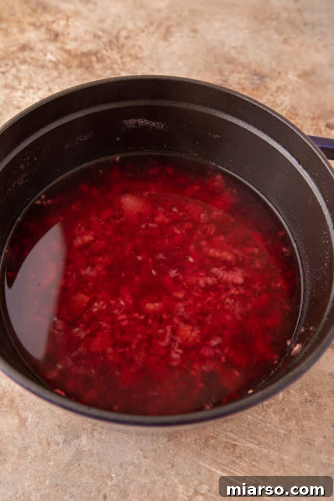 simmering fruit in a pot with water and sugar, transforming into raspberry syrup