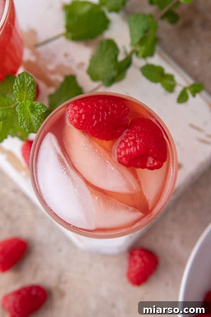 Overhead shot of the raspberry iced tea recipe in a glass with ice and garnished with fresh raspberries