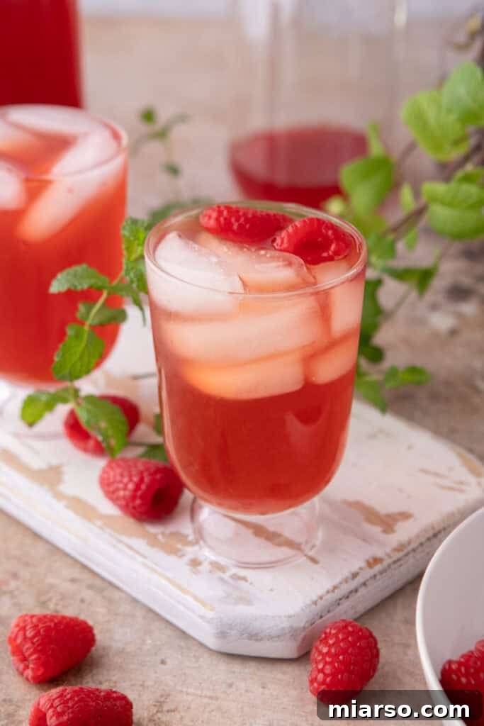 Side shot of the raspberry iced tea recipe in a glass of ice with a straw, ready to drink