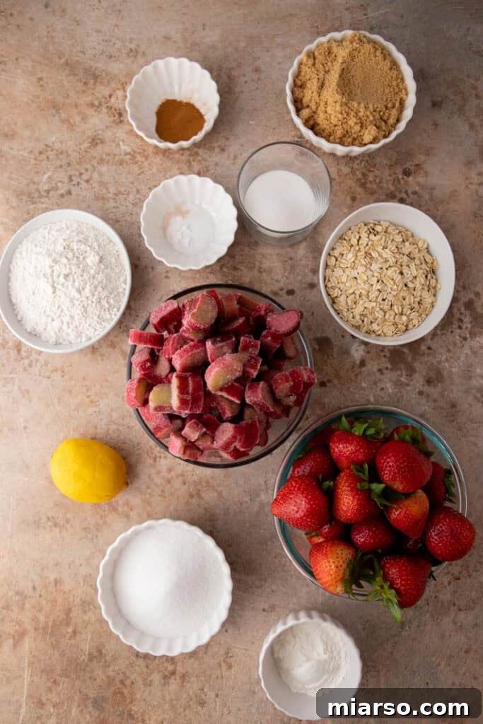 Your New Favorite Strawberry Rhubarb Crisp 3 Fresh ingredients for Strawberry Rhubarb Crisp laid out: chopped rhubarb, hulled strawberries, oats, flour, sugars, and butter.