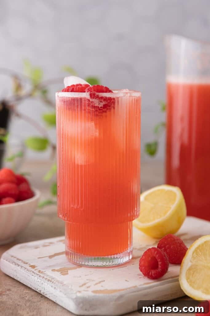 A refreshing glass of homemade raspberry lemonade with ice and fresh raspberries