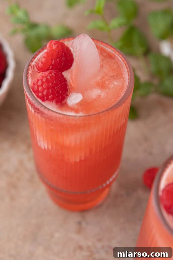 Overhead shot of freshly made raspberry lemonade in a large pitcher with glasses