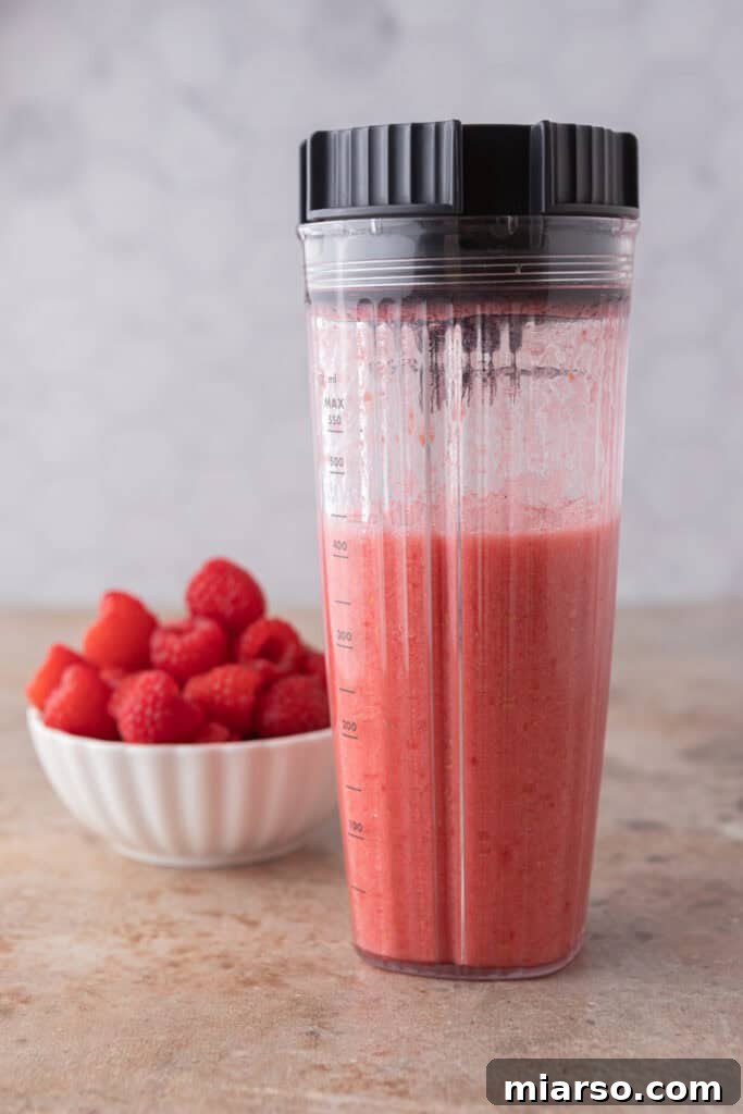 Raspberries and water blending in a blender for the recipe