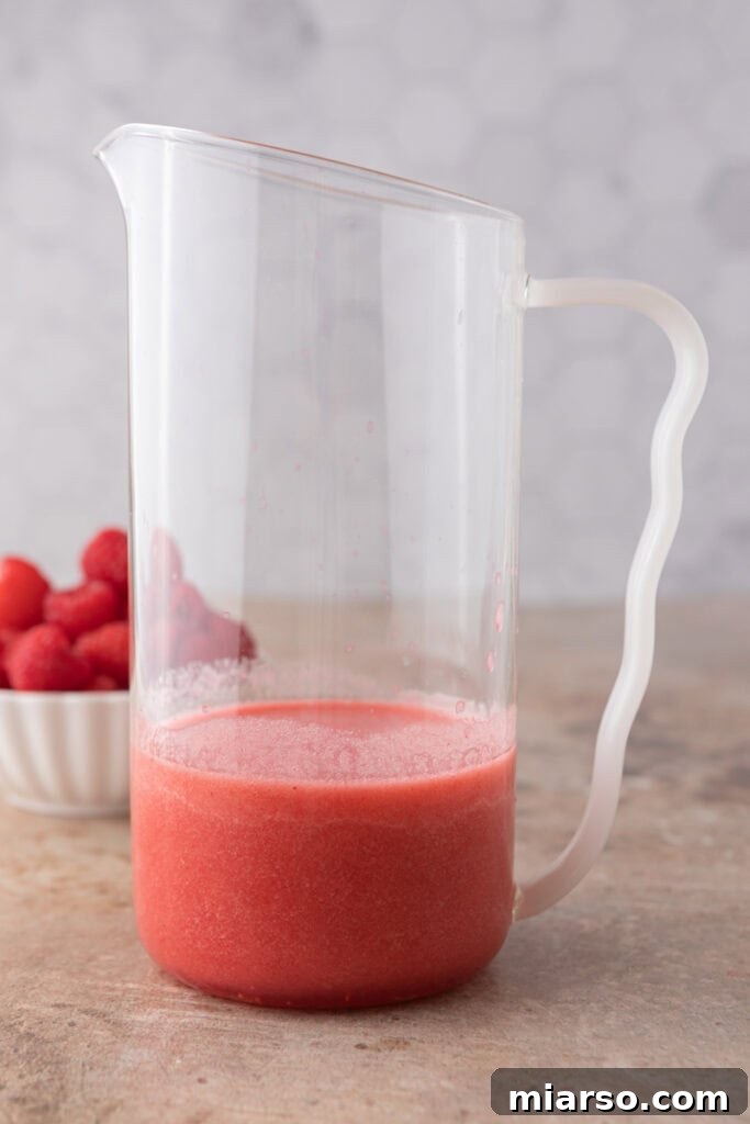 Partially filled pitcher with raspberry puree and lemon juice