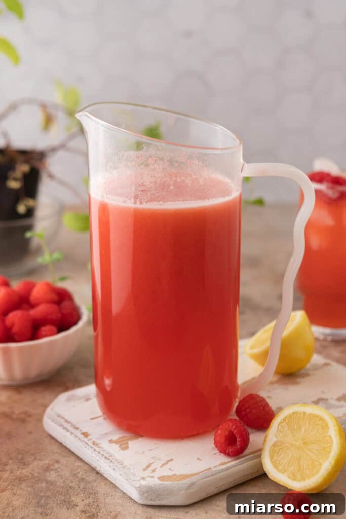 A large pitcher of homemade raspberry lemonade on a table