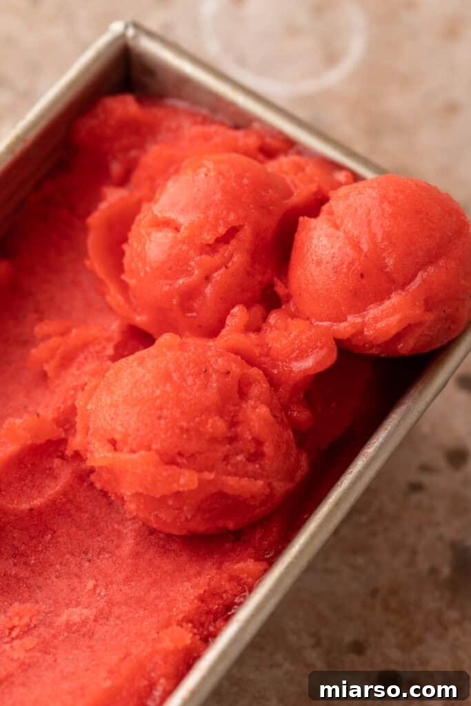 A refreshing loaf pan filled with vibrant frozen strawberry puree, ready to be scooped.