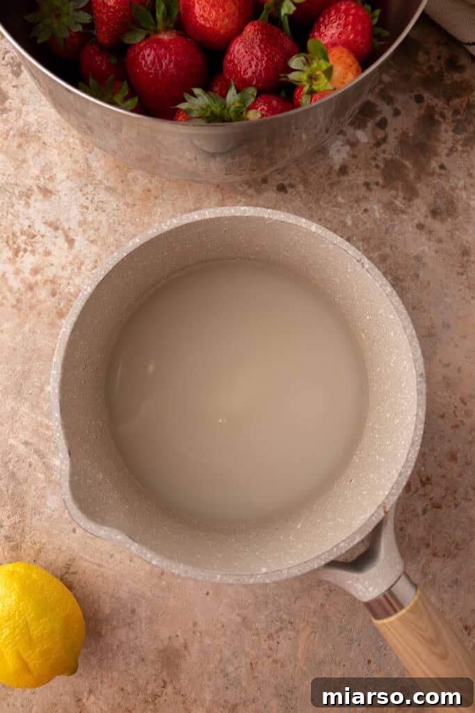 Granulated sugar and water simmering in a small pot, forming a simple syrup.