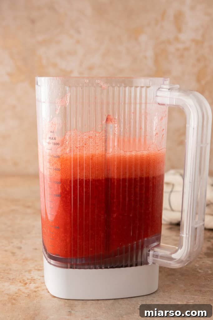 Smoothly blended strawberry puree swirling in a blender.