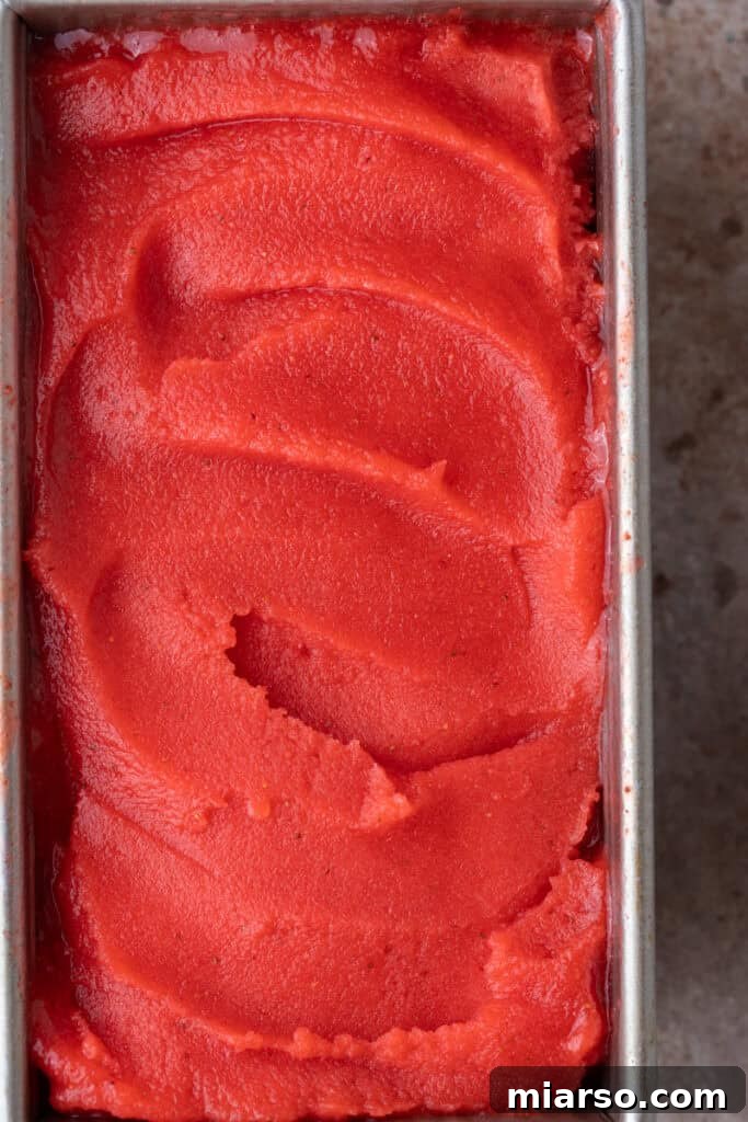 Freshly churned, soft-serve consistency strawberry sorbet in a loaf pan.