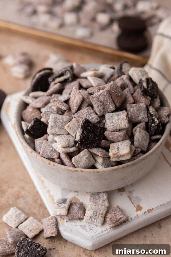 Overhead shot of the Cookies and Cream Muddy Buddies in a bowl, showing the white and dark chocolate coated cereal with Oreo pieces.