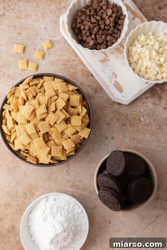 Ingredients for Cookies and Cream Muddy Buddies laid out on a table, including Chex cereal, Oreos, chocolate chips, and powdered sugar.