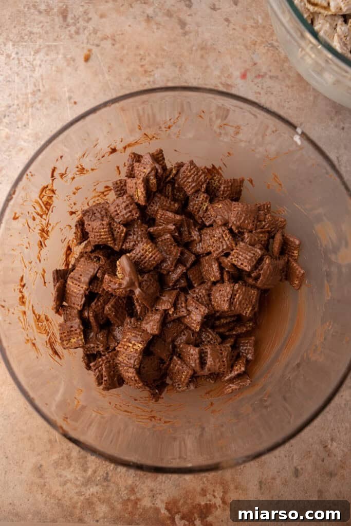 Milk chocolate chips being mixed with Chex cereal in a bowl with a spatula.