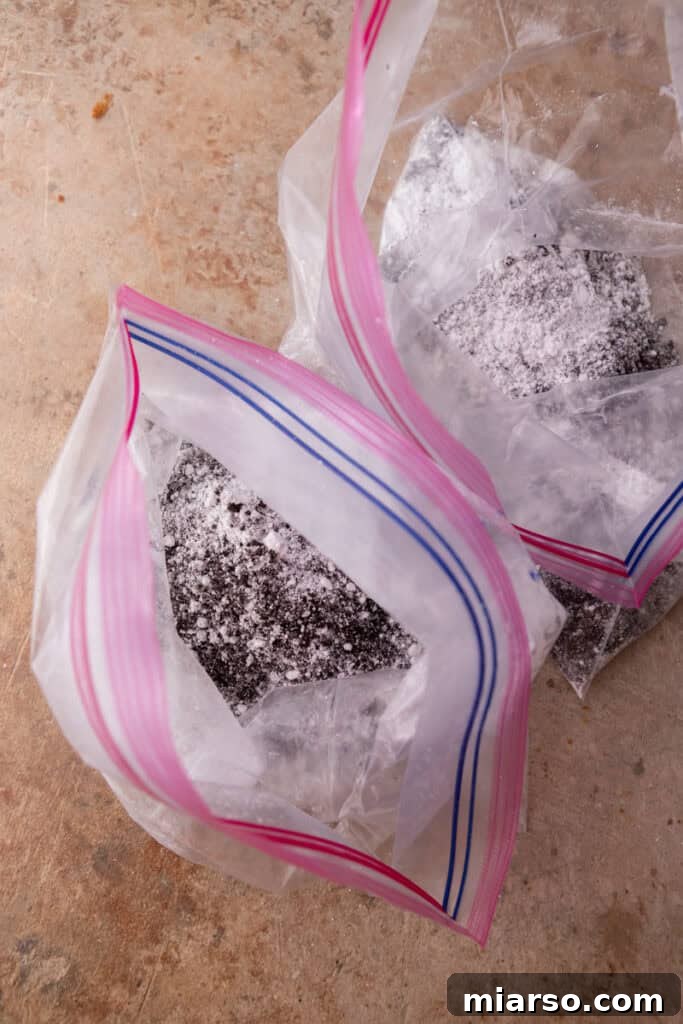 Powdered sugar and crushed Oreos being mixed with chocolate-coated Chex cereal in a large Ziploc bag.