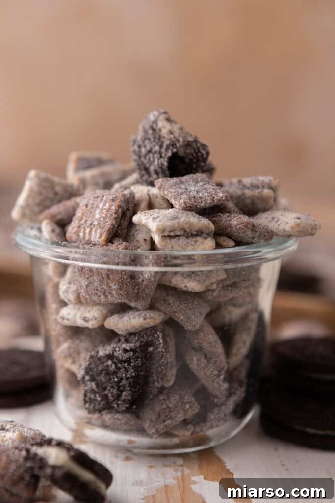 Cookies and Cream Muddy Buddies served in a small cup, ready for snacking.