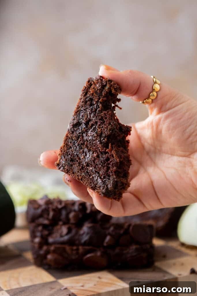 Decadent Double Chocolate Zucchini Loaf 4 A hand holding a slice of Double Chocolate Zucchini Bread, showing its rich, fudgy interior