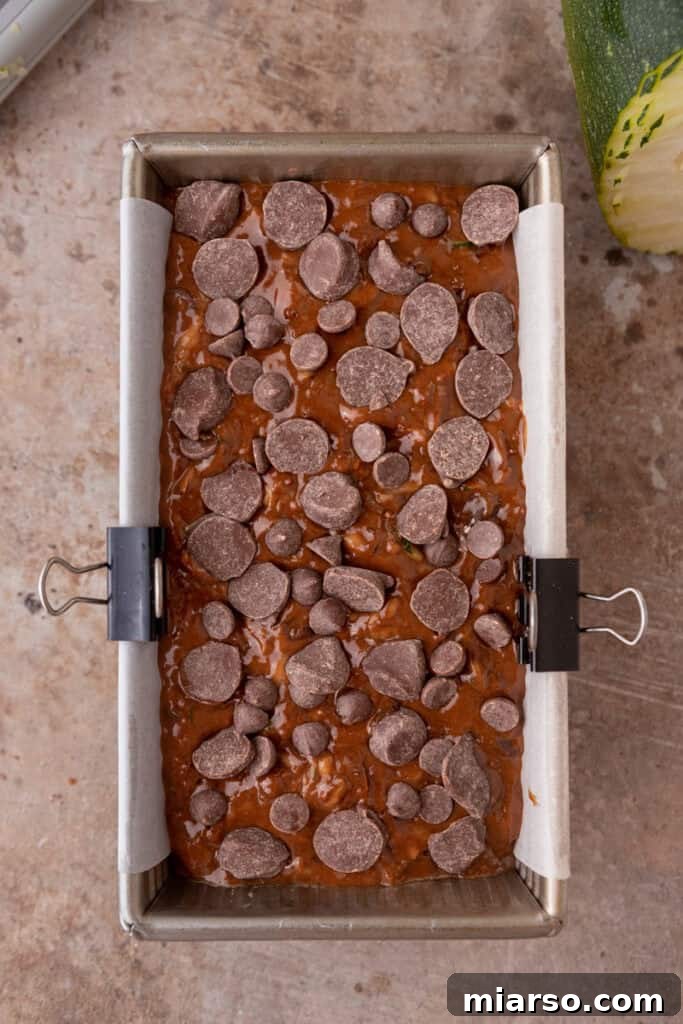 Decadent Double Chocolate Zucchini Loaf 9 Raw double chocolate zucchini bread batter poured into a loaf pan, topped with extra chocolate