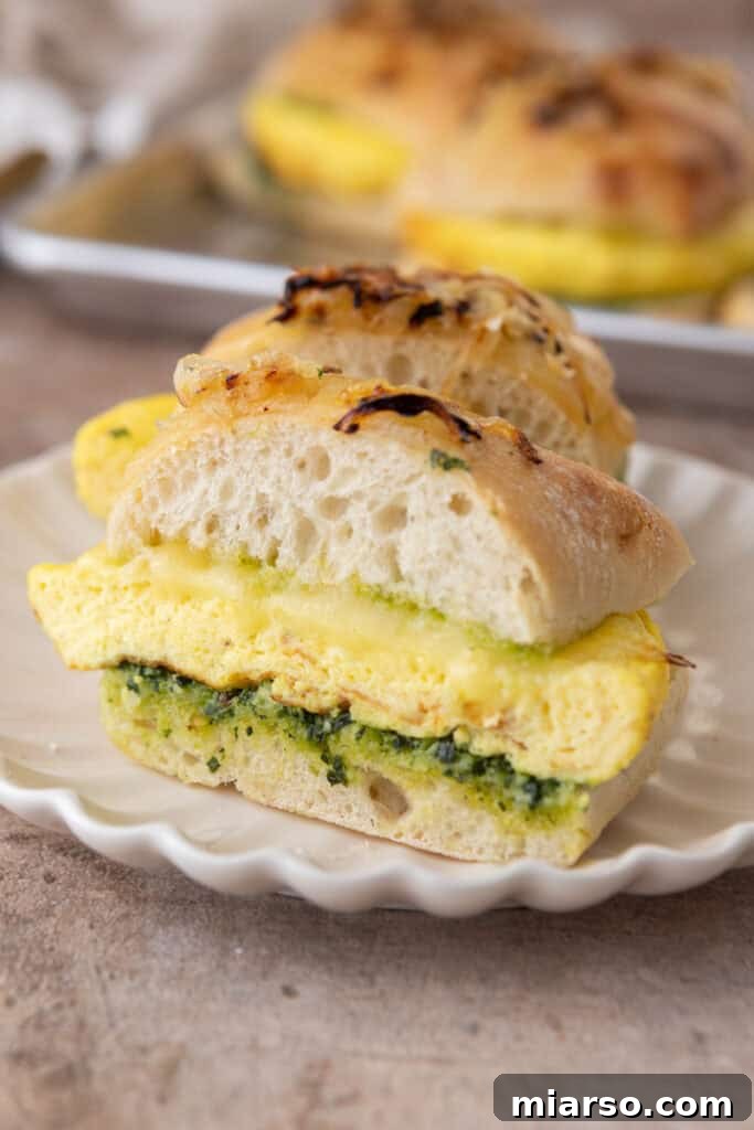 A Starbucks Egg Kale Pesto Mozzarella Sandwich copycat recipe cut in half, revealing its vibrant layers of egg, pesto, and cheese.