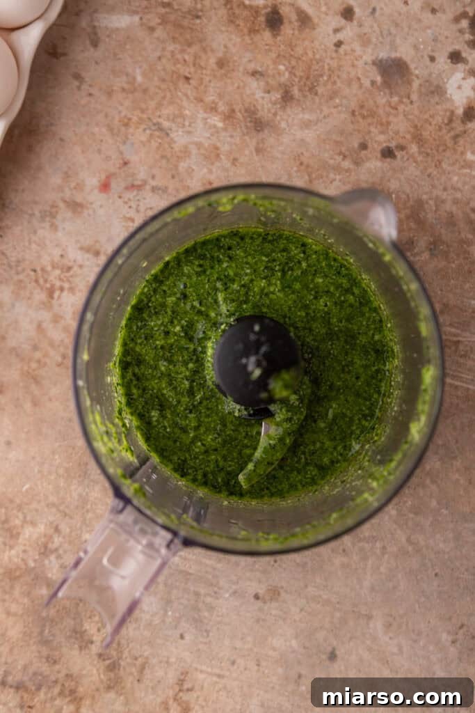 Blended kale and basil pesto in a food processor, showcasing its smooth, vibrant green texture for the Starbucks sandwich.