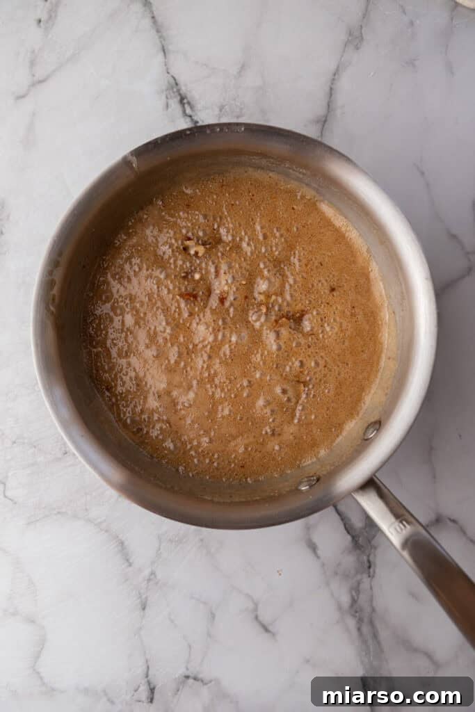 Partially cooked praline mixture in a pot, showing the process of sugar melting and combining with other ingredients.