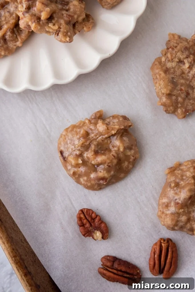 Overhead view of several New Orleans praline patties cooling on parchment paper, displaying their irregular, handmade shape.