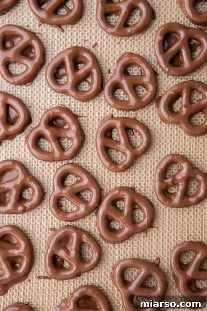 Sweet and Salty Chocolate Pretzel Delight 11 Freshly dipped and decorated chocolate pretzels resting on a baking sheet, allowing the chocolate to set.
