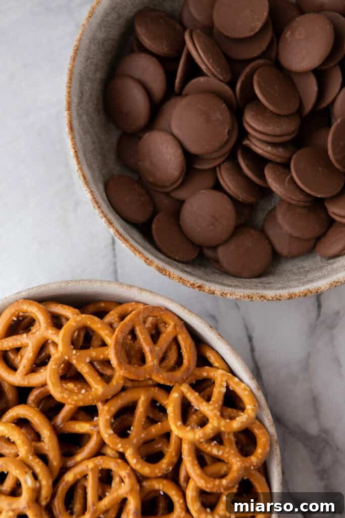 Sweet and Salty Chocolate Pretzel Delight 3 Various ingredients laid out for making chocolate-covered pretzels, including pretzels, chocolate chips, and optional sprinkles.