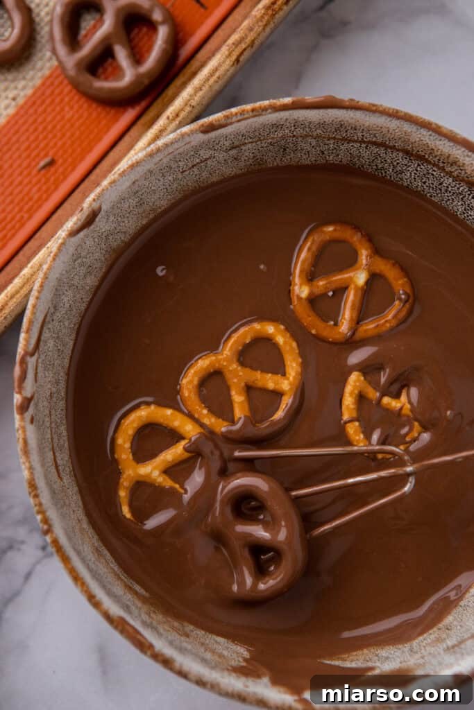 Sweet and Salty Chocolate Pretzel Delight 6 A pretzel being dipped into smooth melted chocolate.