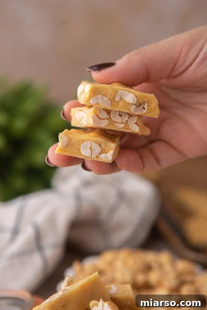 A hand holding up a piece of perfectly crisp microwave peanut brittle.