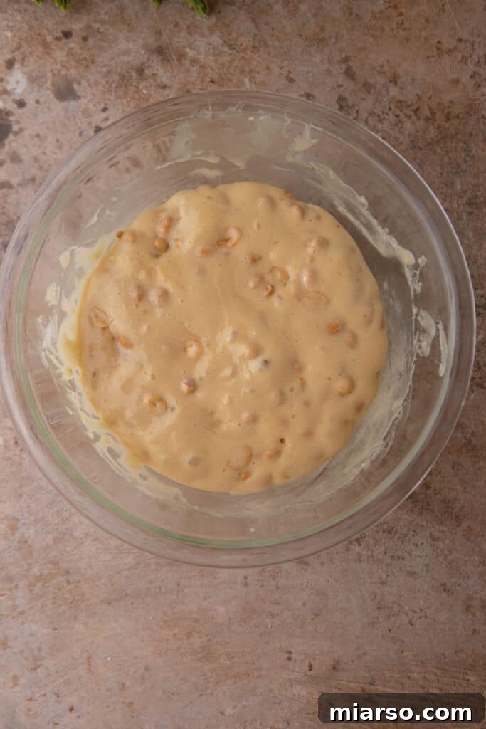 Baking soda being stirred into the hot brittle mixture, causing it to foam.