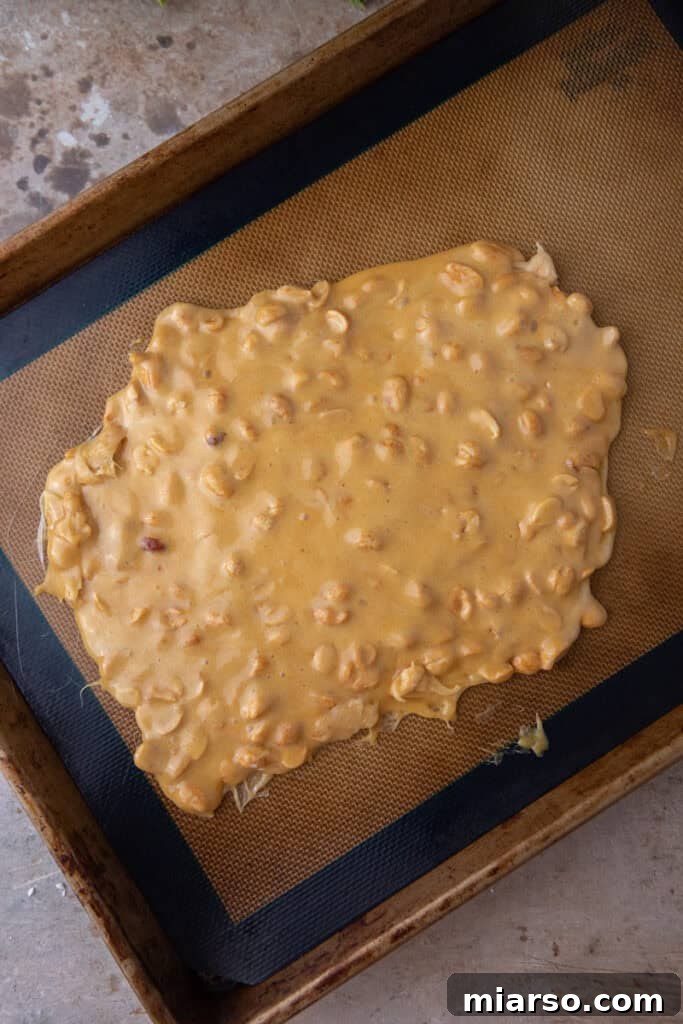 Finished peanut brittle cooling on a parchment-lined pan.