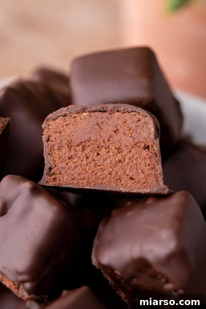 Effortless Three Musketeers Cool Whip Treats 2 Close-up of cool whip candy cut in half, showing the fluffy 3-Musketeers, style chocolate center coated in smooth dark chocolate.