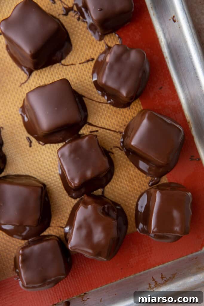 Effortless Three Musketeers Cool Whip Treats 11 Chocolate-coated candy squares setting on a silicone baking mat.