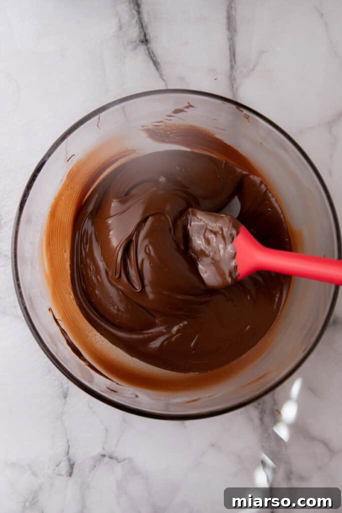 Effortless Three Musketeers Cool Whip Treats 5 Melted dark chocolate in a mixing bowl ready for dipping homemade candy.