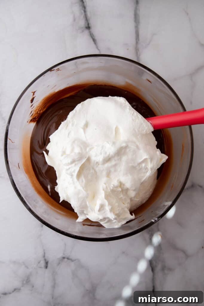 Effortless Three Musketeers Cool Whip Treats 6 Cool Whip added to a bowl of melted chocolate to create the fluffy candy mixture.