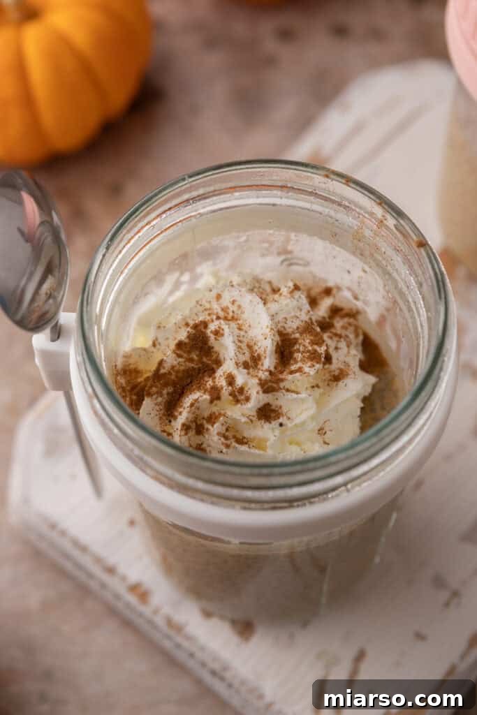 Creamy Pumpkin Spice Chia Seed Pudding 7 An overhead view of several jars filled with Easy Pumpkin Pie Spice Chia Seed Pudding, garnished with pumpkin seeds and cinnamon, ready for meal prep.