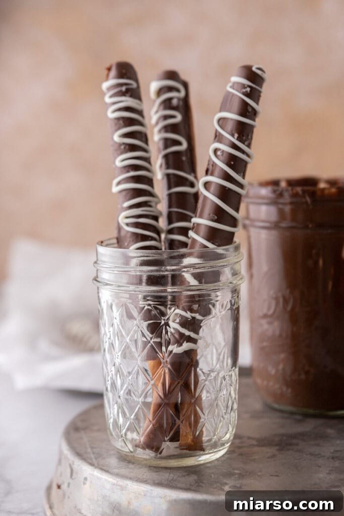 Decadent Caramel Chocolate Pretzel Rods 2 Three decadent caramel chocolate covered pretzel rods, perfectly adorned with sea salt, resting in an elegant cup.