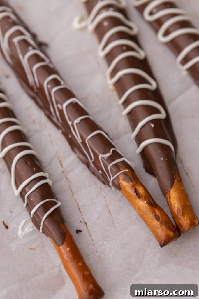 Decadent Caramel Chocolate Pretzel Rods 12 A close-up shot of three caramel chocolate covered pretzel rods, perfectly set on a sheet pan, ready to be enjoyed or packaged.