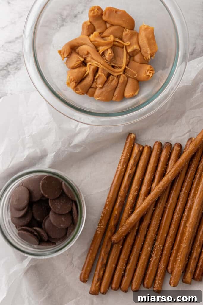Decadent Caramel Chocolate Pretzel Rods 3 Close-up of the essential ingredients for making caramel chocolate covered pretzel rods, including pretzel rods, soft caramels, and chocolate melting wafers.