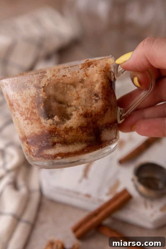 Hand holding up an empty cup, symbolizing a finished and enjoyed snickerdoodle mug cake