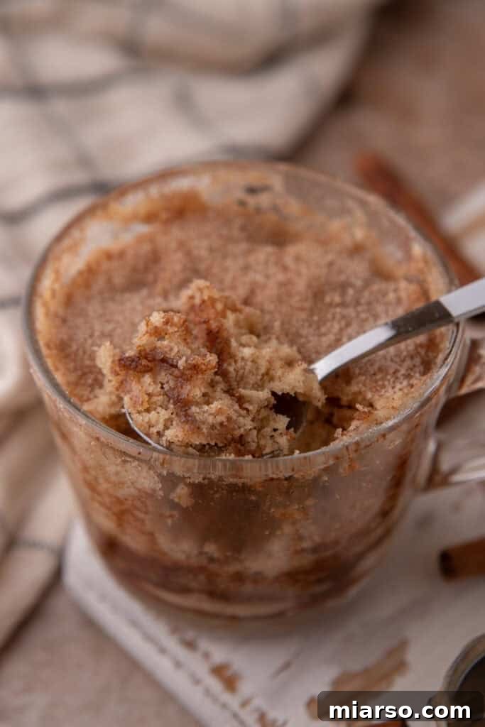 Snickerdoodle mug cake recipe in a cup getting scooped, emphasizing its texture