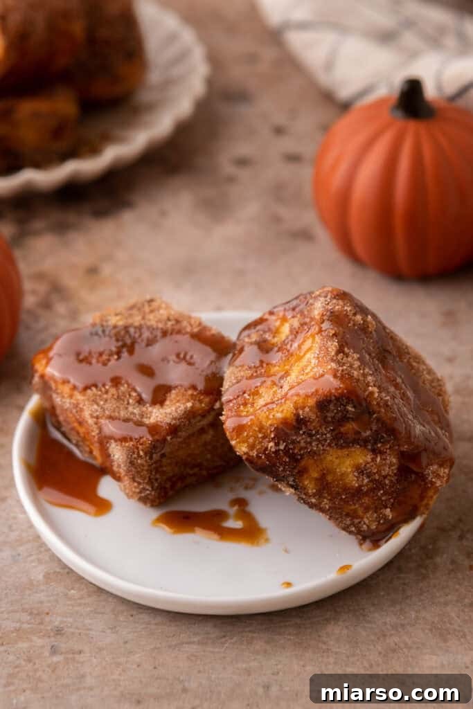 Overhead view of several Hawaiian Roll Pumpkin French Toast bites artfully arranged on a clean white plate, ready to be enjoyed.