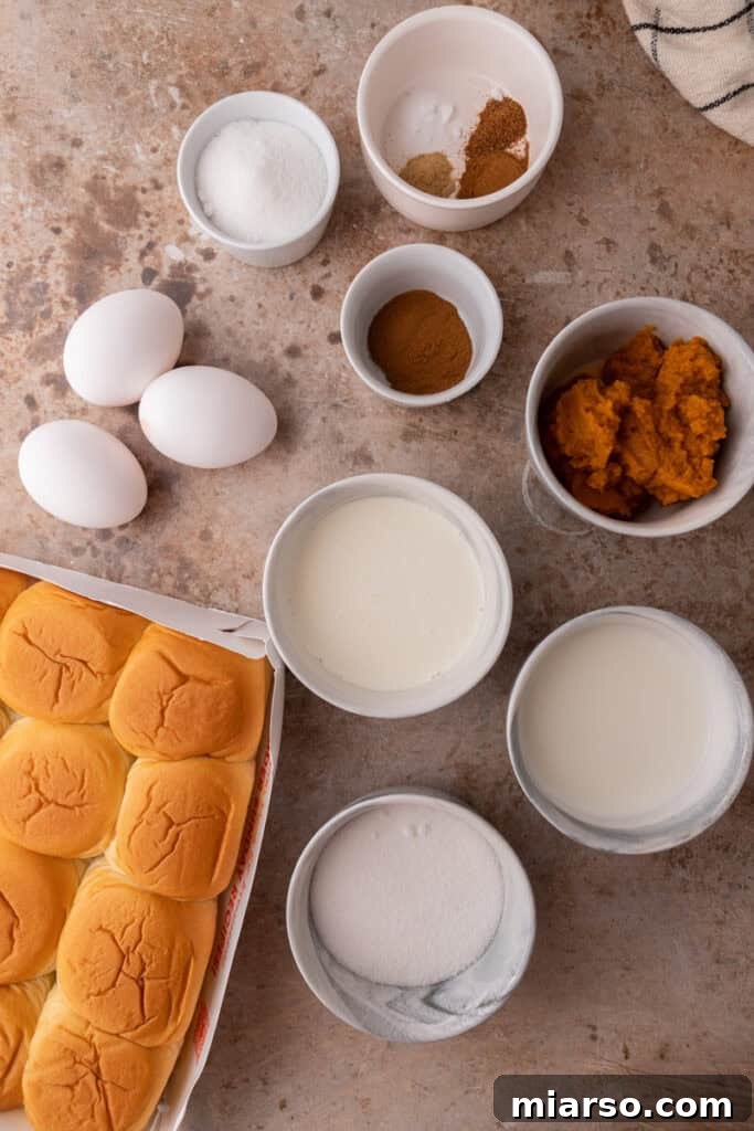 All the fresh ingredients required for the Hawaiian Roll Pumpkin French Toast recipe laid out on a kitchen counter, showcasing the vibrant colors of pumpkin puree, milk, eggs, and spices.