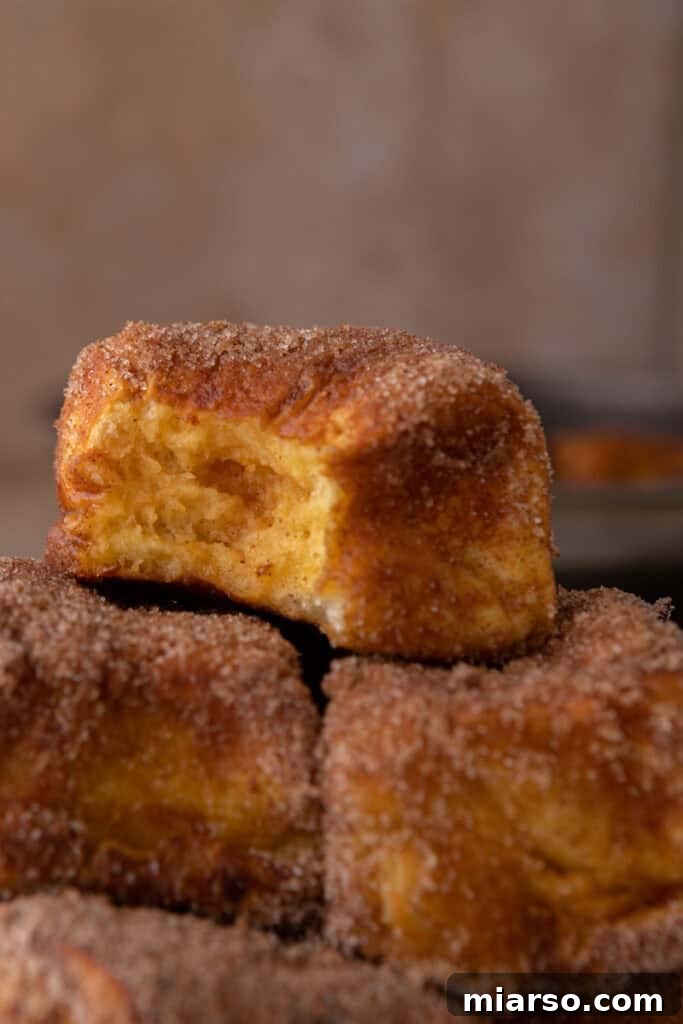 A close-up view of a cooked Hawaiian Roll Pumpkin French Toast, perfectly golden brown and coated in cinnamon sugar, resting on a plate.