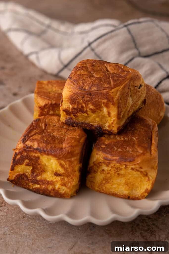 Fully cooked pumpkin French toast bites, golden brown and coated with cinnamon sugar, piled on a plate.