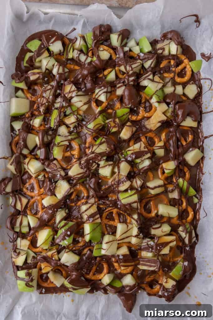 The Ultimate Caramel Apple Bark Recipe 8 chocolate on top of the pretzels and other ingredients
