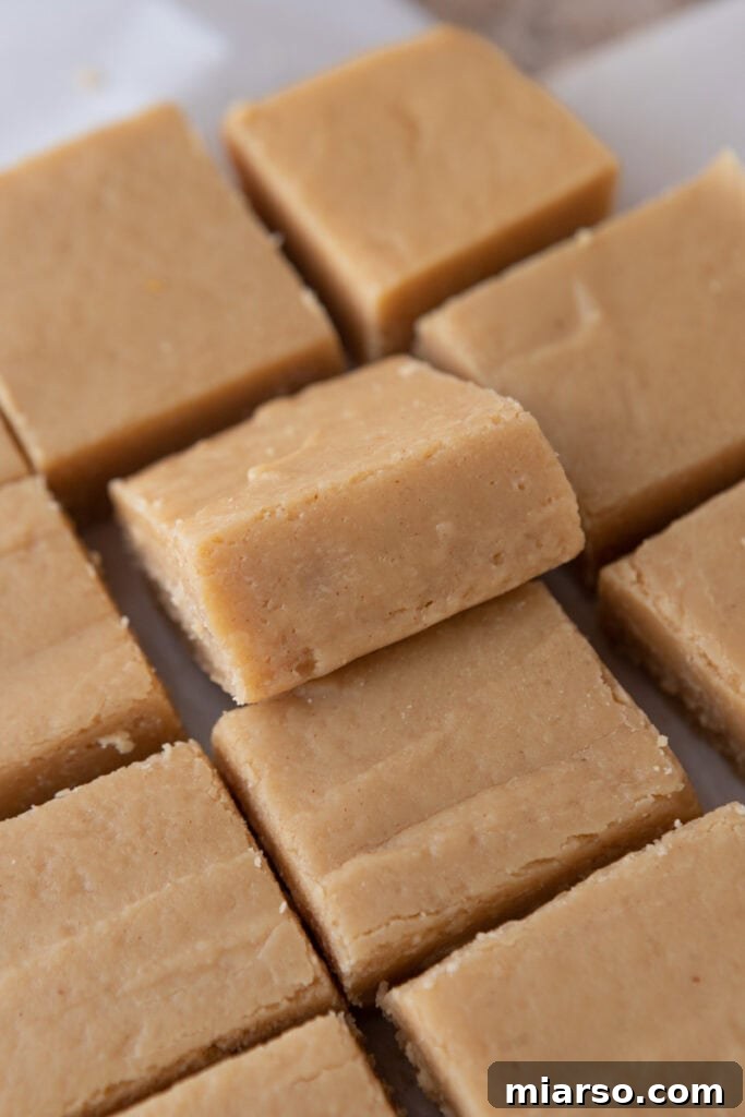 Effortless Microwave Peanut Butter Fudge 10 Perfectly cut squares of microwave peanut butter fudge displayed on a cutting board.