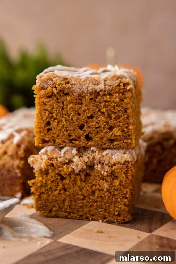 Two generous slices of pumpkin coffee cake, beautifully stacked and glazed, showcasing the moist interior and crumbly topping.